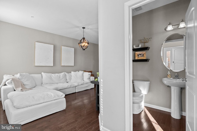 living room featuring an inviting chandelier, dark hardwood / wood-style flooring, and sink