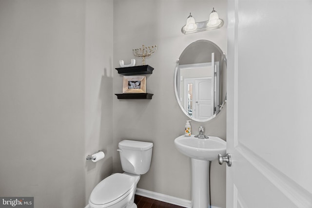 bathroom with toilet, hardwood / wood-style floors, and sink