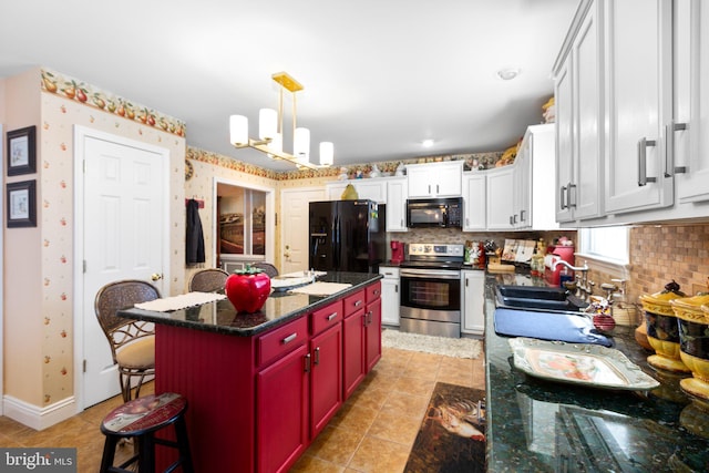 kitchen featuring black appliances, a kitchen island, dark stone counters, an inviting chandelier, and sink