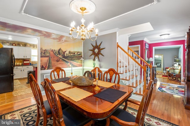 dining space with a chandelier, crown molding, and light hardwood / wood-style flooring