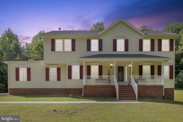 colonial home with a yard and covered porch