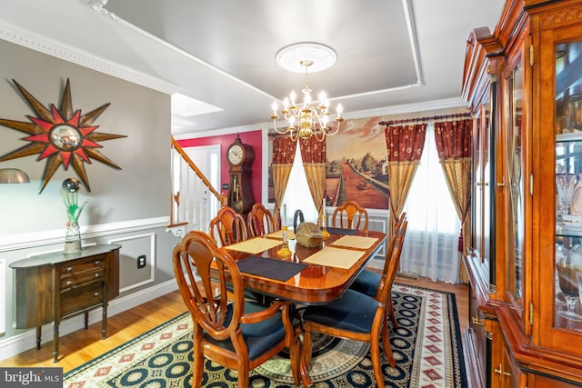 dining space featuring ornamental molding, a chandelier, and light hardwood / wood-style flooring