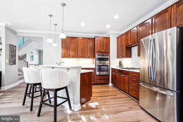 kitchen with a breakfast bar, backsplash, stainless steel appliances, ornamental molding, and decorative light fixtures