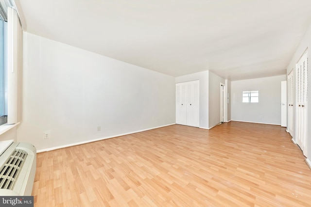 unfurnished living room featuring light hardwood / wood-style floors and a wall mounted air conditioner