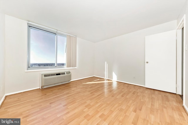 unfurnished living room with an AC wall unit and light hardwood / wood-style floors