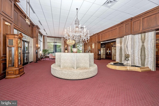 carpeted living room with a chandelier and wooden walls