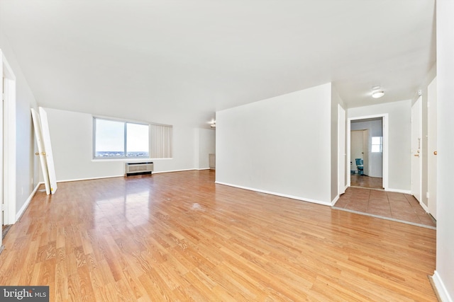 unfurnished living room featuring light wood-type flooring and a wall mounted air conditioner