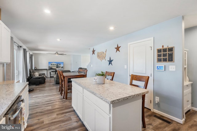 kitchen featuring ceiling fan, a breakfast bar, white cabinetry, and a center island