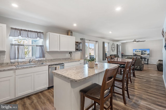 kitchen featuring white cabinetry, dark hardwood / wood-style flooring, a kitchen island, stainless steel dishwasher, and sink