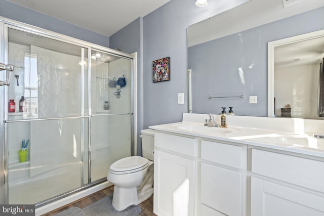 bathroom featuring toilet, vanity, wood-type flooring, and a shower with door