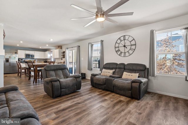 living room with dark wood-type flooring, a healthy amount of sunlight, and ceiling fan