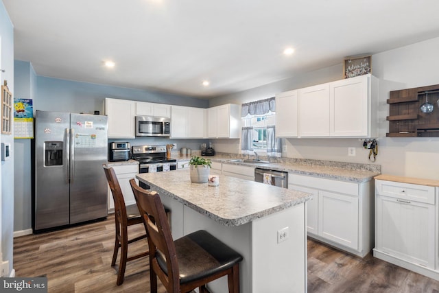 kitchen with white cabinets, a center island, a kitchen bar, stainless steel appliances, and sink