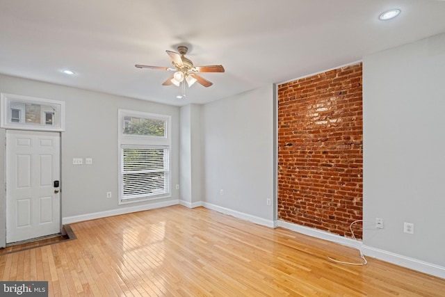 interior space with ceiling fan, light wood-type flooring, and brick wall