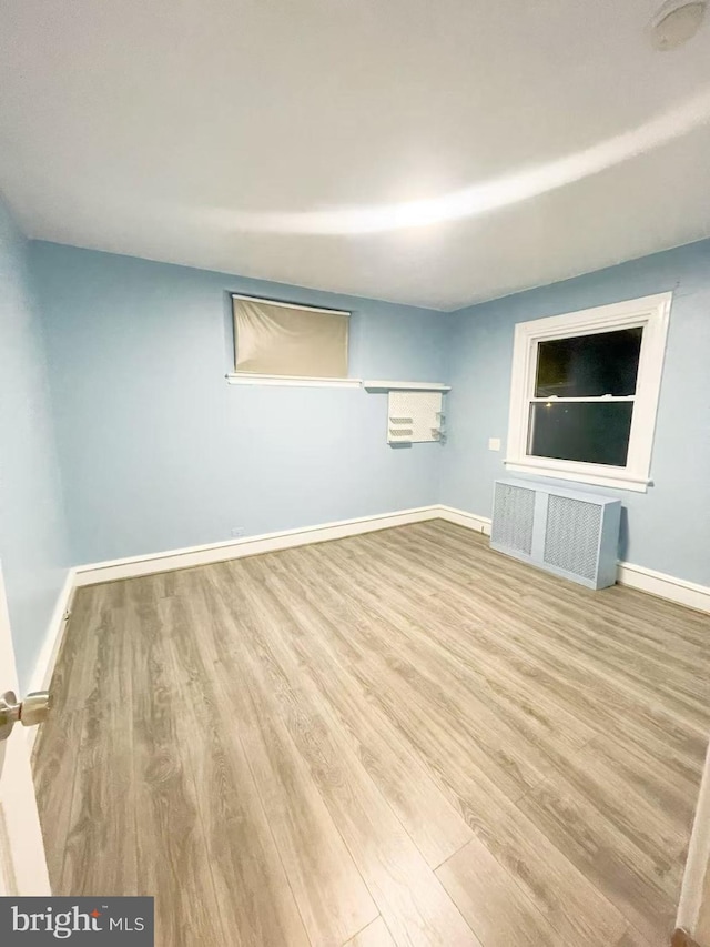 empty room with light hardwood / wood-style flooring and radiator heating unit