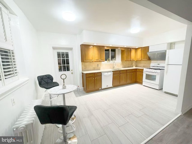 kitchen featuring light hardwood / wood-style floors, backsplash, white appliances, and sink