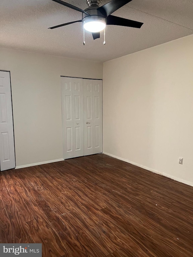 unfurnished bedroom with a closet, a textured ceiling, dark hardwood / wood-style floors, and ceiling fan