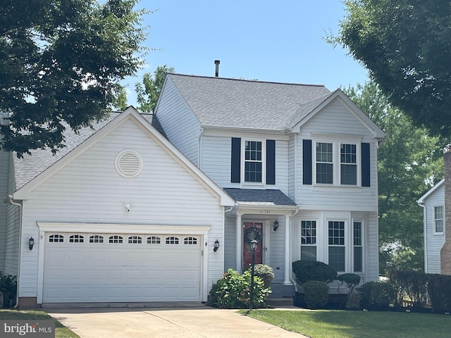 traditional home with a garage, concrete driveway, and roof with shingles