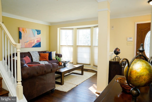 living room featuring dark wood-type flooring, crown molding, decorative columns, and stairway