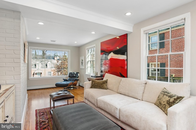 living room with a baseboard radiator, recessed lighting, light wood-style floors, baseboard heating, and crown molding