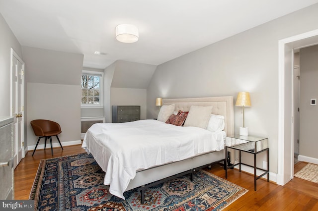 bedroom with vaulted ceiling, wood finished floors, visible vents, and baseboards