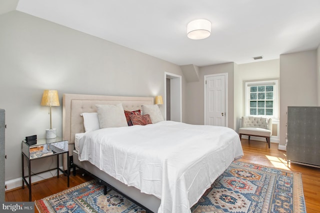 bedroom featuring visible vents, baseboards, and wood finished floors