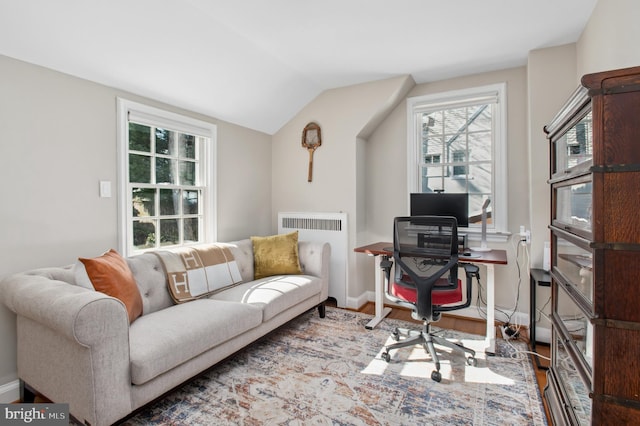 home office featuring radiator, baseboards, wood finished floors, and lofted ceiling