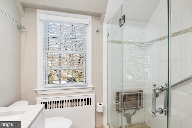 bathroom featuring toilet, radiator heating unit, vanity, and a stall shower