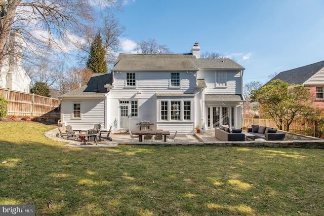 rear view of house featuring a chimney, a patio area, a yard, and a fenced backyard