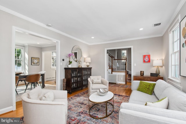 living room with light wood-style floors, stairs, visible vents, and ornamental molding