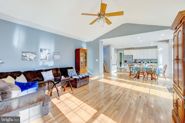 living room with vaulted ceiling, ceiling fan, and light wood-type flooring