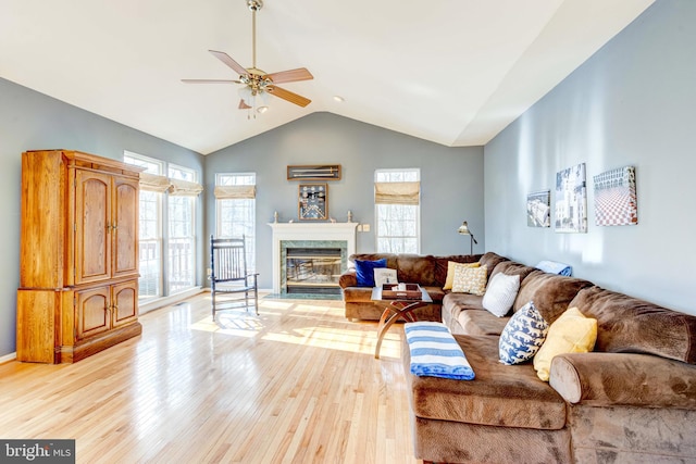 living room featuring a premium fireplace, plenty of natural light, ceiling fan, and light wood-type flooring