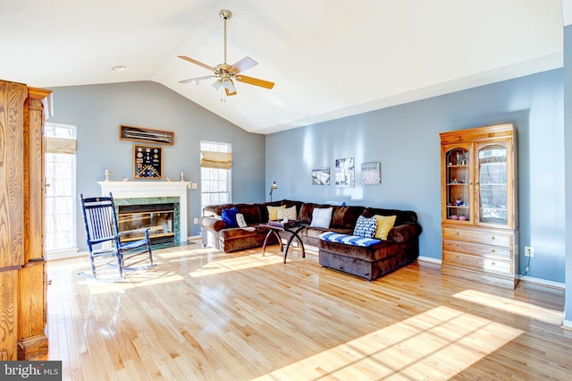 living room with lofted ceiling, a fireplace, ceiling fan, and light wood-type flooring