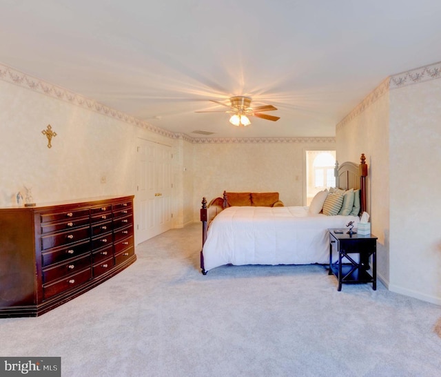 bedroom featuring light colored carpet, ceiling fan, and a closet