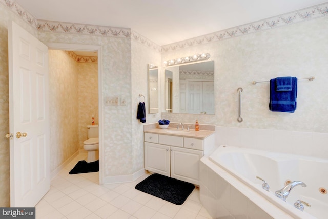 bathroom featuring tile patterned flooring, vanity, tiled bath, and toilet