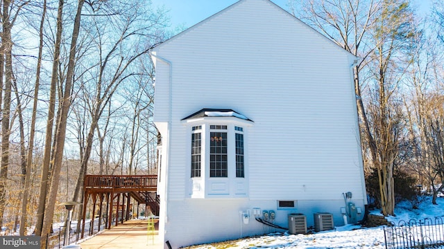 view of snow covered exterior featuring central AC unit and a wooden deck