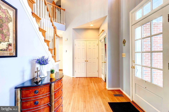 entryway featuring a towering ceiling and light wood-type flooring