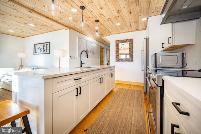 kitchen featuring decorative light fixtures, sink, appliances with stainless steel finishes, an island with sink, and wooden ceiling