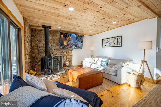 living room with light hardwood / wood-style flooring, wood ceiling, and a wood stove