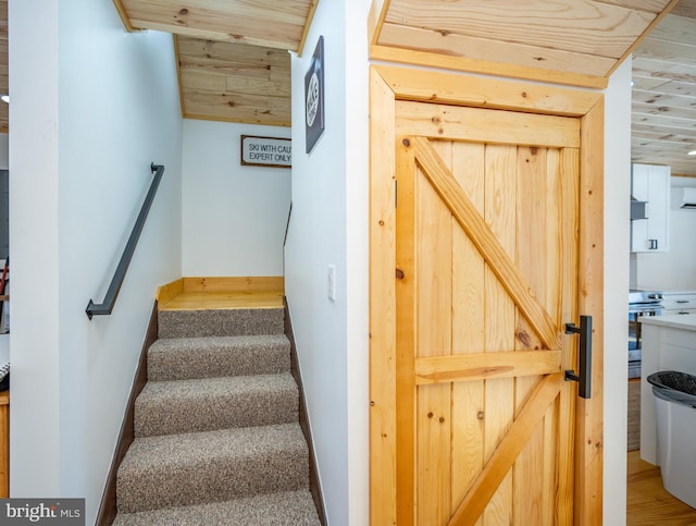 stairs with carpet floors and wood ceiling