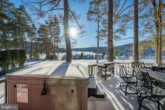 snow covered deck with a mountain view and a hot tub