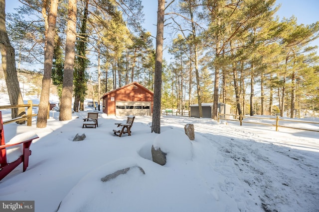 yard layered in snow featuring a garage and an outbuilding