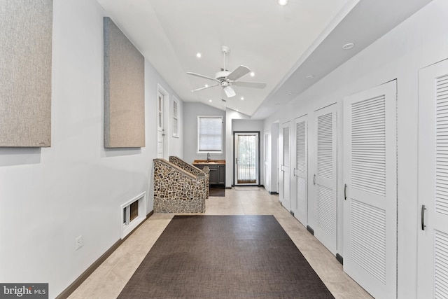 corridor with light tile patterned floors and vaulted ceiling