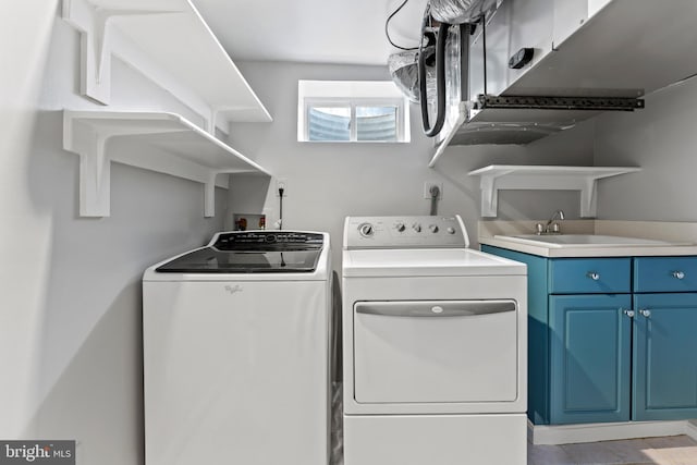 washroom with cabinets, washing machine and dryer, and sink