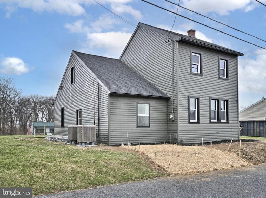 view of property exterior with central AC and a yard