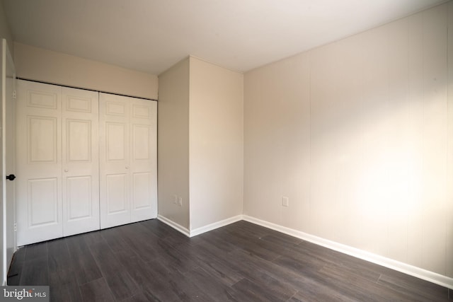 unfurnished bedroom featuring dark wood-type flooring and a closet