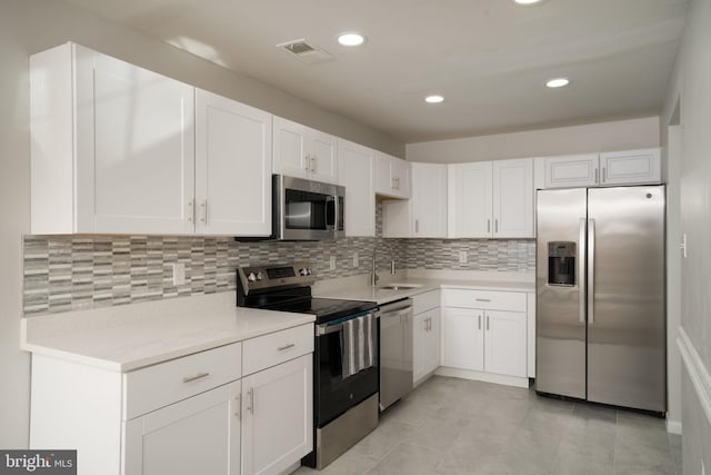 kitchen with white cabinetry, stainless steel appliances, sink, and decorative backsplash