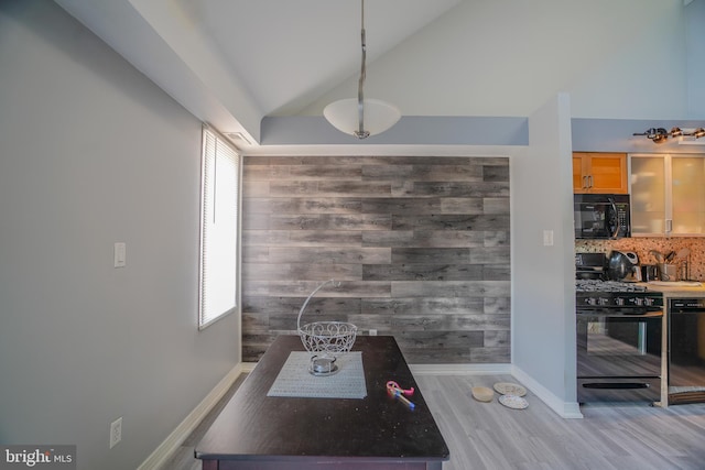 dining area featuring lofted ceiling, wooden walls, and hardwood / wood-style flooring