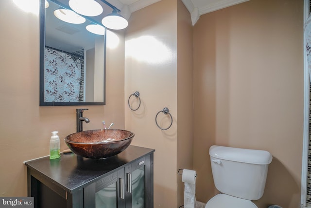 bathroom with toilet, vanity, and crown molding