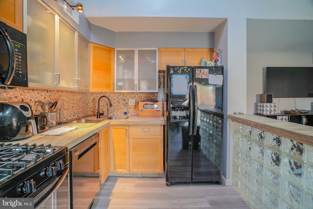 kitchen with black appliances, decorative backsplash, sink, light wood-type flooring, and light brown cabinetry