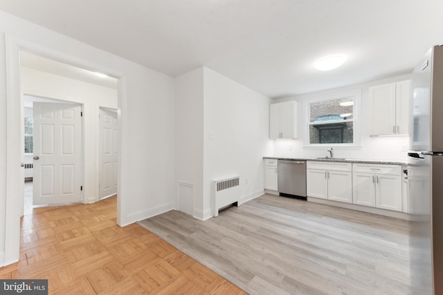 kitchen featuring sink, white cabinets, radiator heating unit, and stainless steel appliances